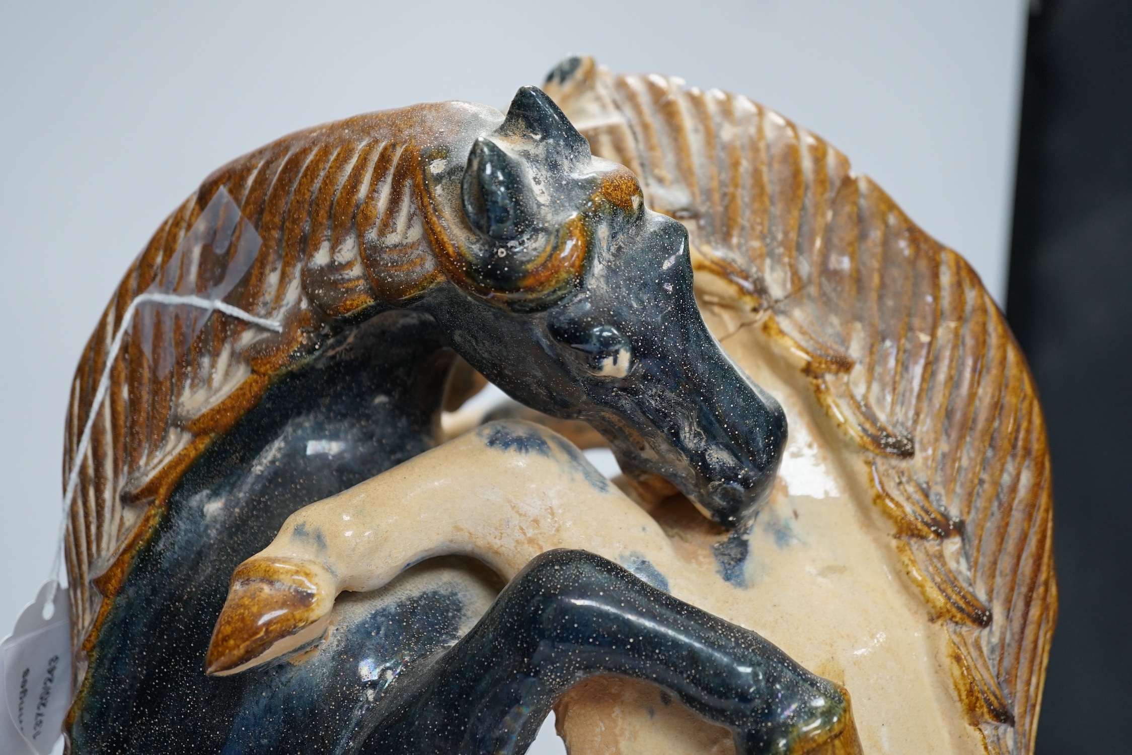 A Chinese sancai glazed group of fighting horses, Tang or later, 39cm high